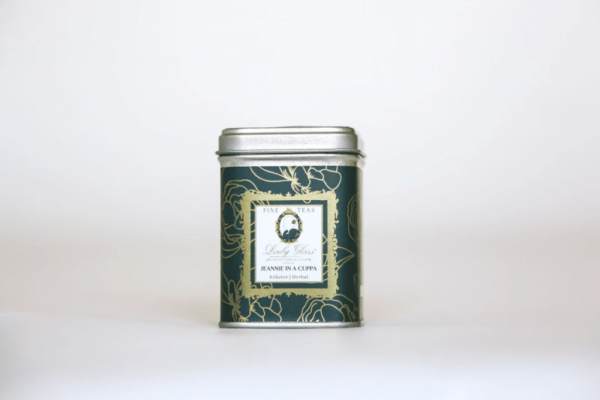 Fine loose leaf herbal tea in a green tea caddy on white background