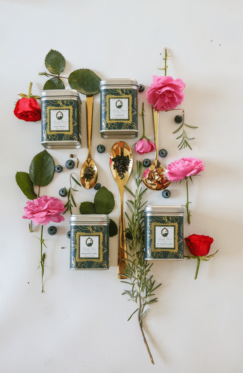 Premium loose leaf black teas in green tea caddies surrounded with gold spoons and roses
