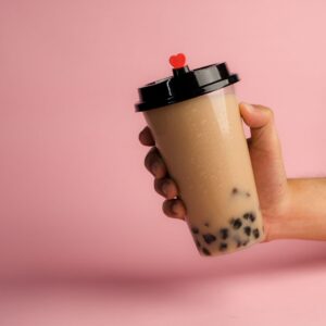 A person holding a milk tea with black pearls