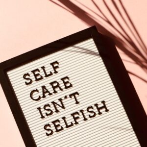 Self-care isn't selfish written on a journal with a pink background